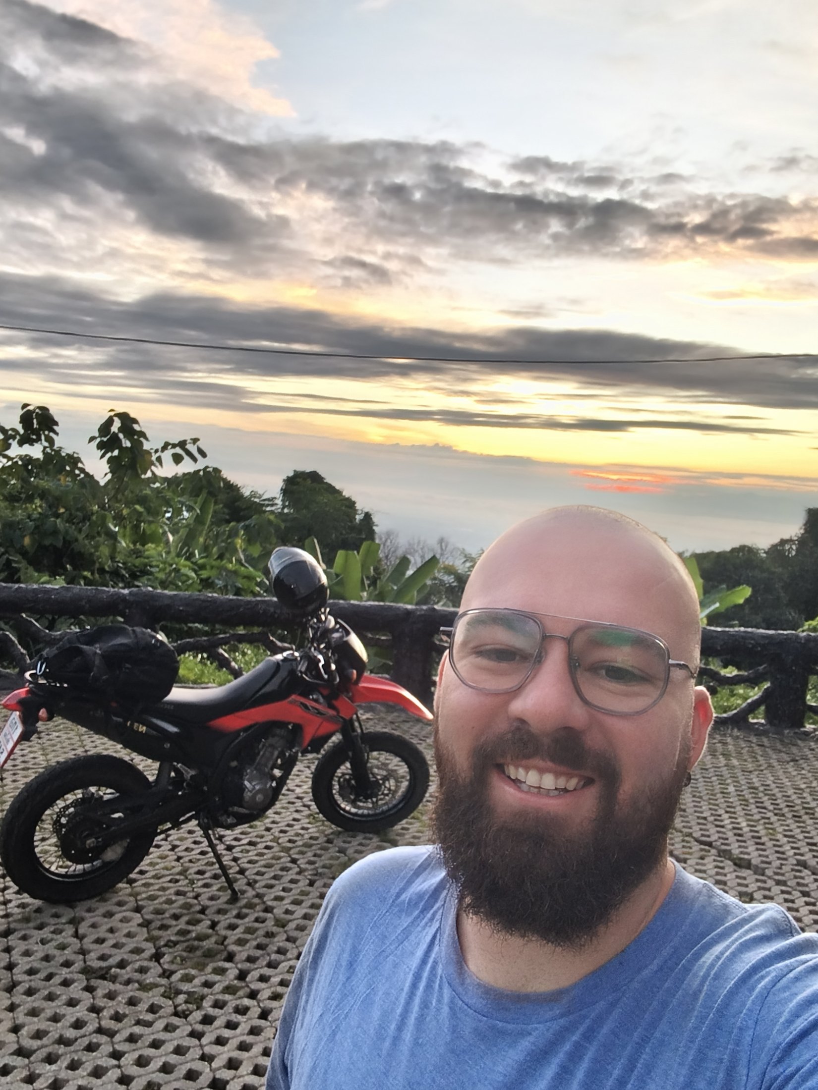 Reed wearing NOVARO frames at a mountain sunset viewpoint in Chiang Mai